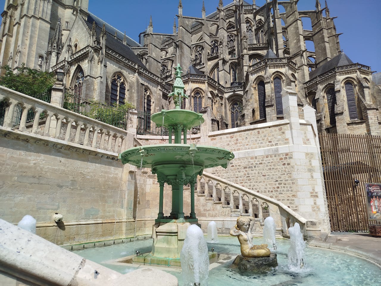 Historic cathedral with a green fountain in Reims, perfect for travel photos.